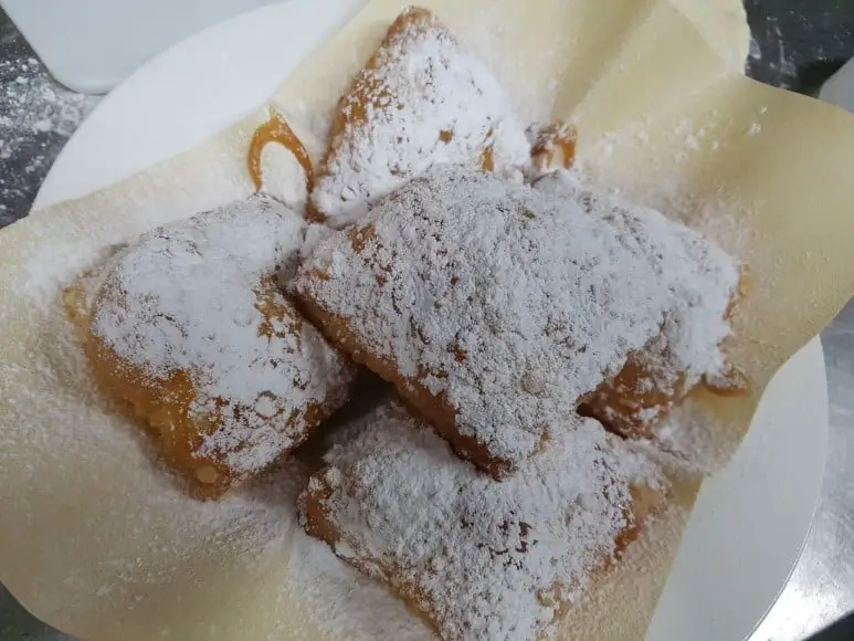 a plate of beignet with a light dusting of sugar on top dessert